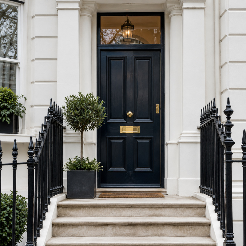 A black front door and railings on a white London townhouse